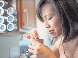  ??  ?? RIGHT Christine Ha, a cook and writer who is blind, smells a spice container to check its contents, at her home in Houston.