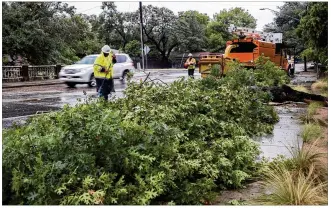  ?? MARK MATSON / FOR AMERICAN-STATESMAN ?? Austin city workers clean up debris from a fallen limb on Shoal Creek Boulevard near Woodview Avenue after early morning rains Monday. The limb took down a power line and blocked the street, causing traffic to be diverted. Monday’s downpours had...