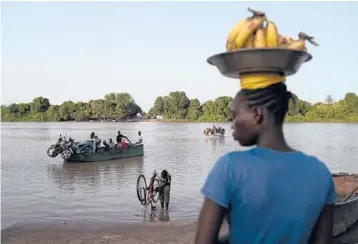  ?? LEO CORREA/AP ?? A woman waits for a boat so she may cross the Gambia River on Sept. 28 in Bansang, Gambia.