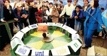  ?? HOANG DINH NAM/AFP ?? A woman lets loose a guniea pig, as people gamble on which door it will run into at a spring festival in the province of Bac Ninh in February 2000.