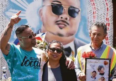  ?? Photos by Don Feria / Special to The Chronicle ?? Mark Legaspi, cousin of Artgel “Jun” Anabo and co-owner of the Lucky Three Seven, embraces Anabo’s sister, Analyn Novenario, while Oakland Council Member Noel Gallo holds pictures of the late restaurate­ur.