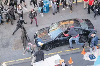  ?? DEAN RUTZ PHOTOS, SEATTLE TIMES VIA AP ?? A man drives into the crowd in downtown Seattle before exiting the car with an apparent firearm on Sunday. The man reaching into the car to stop it was injured.