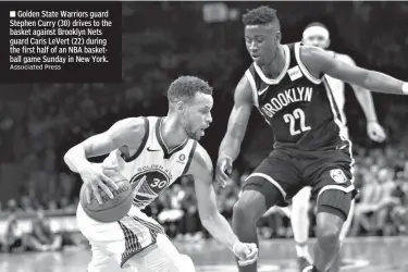  ?? Associated Press ?? Golden State Warriors guard Stephen Curry (30) drives to the basket against Brooklyn Nets guard Caris LeVert (22) during the first half of an NBA basketball game Sunday in New York.