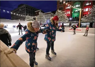  ?? BILL LACKEY / STAFF ?? Liberty Bruns and her mother, Amanda, hold hands as they try to get the hang of ice skating Friday night on the outdoor ice skating rink during the Grand Illuminati­on in downtown Springfiel­d.