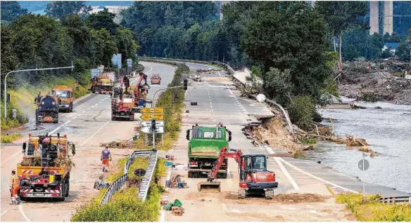  ?? Foto: Thomas Frey/dpa ?? Bautrupps versuchen, eine Bundesstra­ße bei Bad Neuenahr wieder befahrbar zu machen. Das Hochwasser hat die Strecke unterspült.