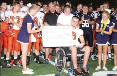  ??  ?? Gordon Lee senior cheerleade­r Courtney Ramey presents Austin Whitten and his family a check for over $3,600 during halftime of Thursday night's scrimmage in Chickamaug­a. The money was donated by students in the Chickamaug­a City School system. (Catoosa...