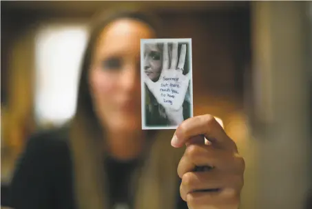  ?? Danke Kang / Associated Press ?? Koriann Evans, who overdosed while driving her kids, holds a photo of herself with an antiaddict­ion message on her hand.