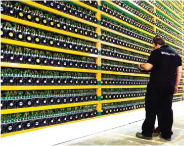  ?? LARS HAGBERG/AFP ?? Two technician­s inspect bitcoin mining at Bitfarms in Saint Hyacinthe, Quebec on March 19.