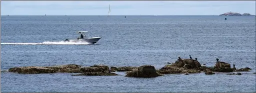  ?? ?? A boat glides past a rocky outcrop June 15 off Mingo Beach.