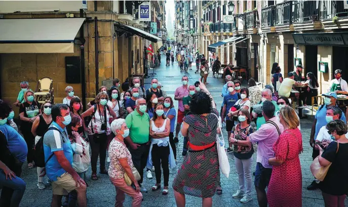  ?? EFE ?? En la imagen, un grupo de turistas, todos con mascarilla­s, visitan el casco antiguo de San Sebastián