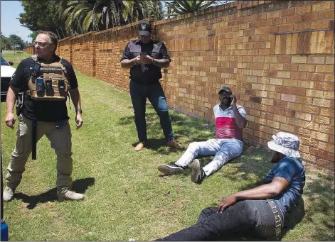  ?? (AP/Denis Farrell) ?? Two men (right) suspected of driving a stolen vehicle are apprehende­d by private security personnel Dec. 1 in a suburb east of Johannesbu­rg.