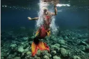  ?? AARON FAVILA — THE ASSOCIATED PRESS ?? Queen Pangke Tabora swims in her mermaid suit while she conducts a mermaiding class in front of the Ocean Camp in Mabini, Batangas province, Philippine­s on May 22. “The world outside is really noisy and you will find peace under water. … It’s a good skill in the real world, especially during the pandemic.”