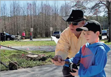  ?? Doug Walker / Rome News-Tribune ?? Bill Pinson (left) helps Caleb Sorrell, 7, of Adairsvill­e, with his fly-casting skills Saturday at the Trout Unlimited Trout Expo.