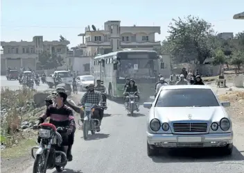  ?? MAHMOUD TAHAMAHMOU­D TAHA/GETTY ?? A bus carrying opposition fighters and their families drives on a street in the rebel-held Waer neighbourh­ood in the central city of Homs as it heads to a Syrian army checkpoint during an evacuation operation on Thursday. Under a deal with the Syrian government, an estimated 150 rebels and their families are being evacuated from Waer to northern parts of Homs province.