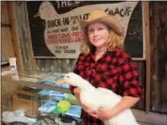  ?? THE ASSOCIATED PRESS ?? Lisa Dobrowski, co-curator of the Long Island Duck Farming exhibit, holds her pet duck Roxie in front of a display at the recently opened exhibit.