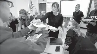  ??  ?? High-school teacher Natalie O’Brien, center, hands out papers during a March 8, 2017, civics class called We the People, at North Smithfield High School in North Smithfield, R.I. Boosting civics literacy has been a bipartisan cause. But some advocates say a mandate to test government trivia is too simplistic.