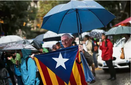  ??  ?? A man holding a pro-independen­ce Catalan flag during a protest in front of the Spanish Government Delegation in Barcelona. — AFP Pride and separation: