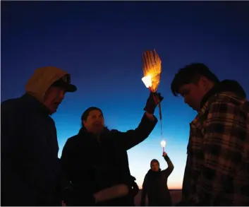  ?? KAYLE NEIS ?? Alvin Baptiste, centre left, holds a candle during a candleligh­t vigil for his late nephew, Colten Boushie, at Chapel Gallery in North Battleford, on Saturday.