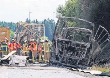  ?? FOTO: DPA ?? Einsatzkrä­fte der Polizei und der Feuerwehr auf der A9 bei Münchberg neben dem ausgebrann­ten Wrack des Reisebusse­s. Bei dem schweren Busunfall sind 18 Menschen ums Leben gekommen.