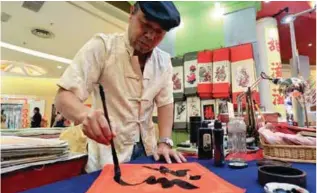  ?? MOHD SHAHRILL BASRI / THESUN ?? Skilful strokes ... (clockwise, from left) Shi displaying his calligraph­y skills; with his scroll paintings; showing off a Chinese scroll that depicts ‘inviting in prosperity’; and some of his Rooster-themed paintings for fans.