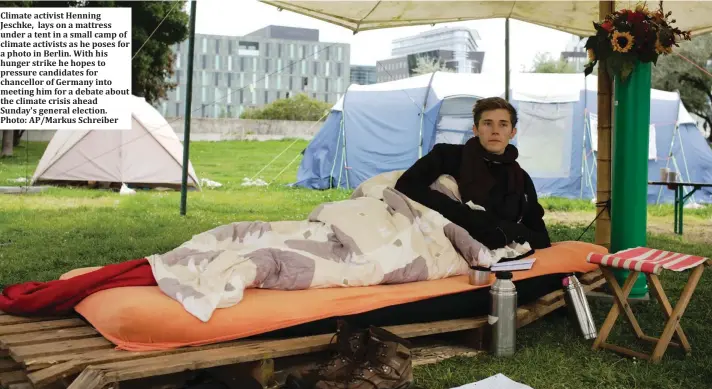  ?? Photo: AP/Markus Schreiber ?? Climate activist Henning Jeschke, lays on a mattress under a tent in a small camp of climate activists as he poses for a photo in Berlin. With his hunger strike he hopes to pressure candidates for chancellor of Germany into meeting him for a debate about the climate crisis ahead Sunday's general election.