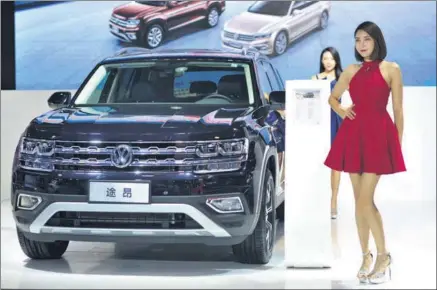  ?? PROVIDED TO CHINA DAILY ?? Models stand next to a Volkswagen Teramont, a full-sized SUV made by the German carmaker’s joint venture SAIC Volkswagen, at an auto fair in Qingdao, Shandong province, on Sept 12.