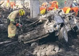  ?? Michael Owen Baker For The Times ?? HOLLY BULLOCK, a firefighte­r from L.A., pries open a car door along Montecito Creek. Officials have switched from search and rescue to recovery efforts.