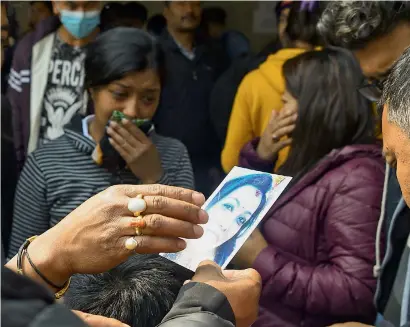  ?? AFP ?? Family members of a plane crash victim hold pictures of their loved ones outside a morgue in Kathmandu on Tuesday. —