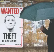  ?? DAVID BLOOM ?? A pedestrian walks past a poster featuring an image criticizin­g Facebook CEO Mark Zuckerberg in Edmonton on June 17.