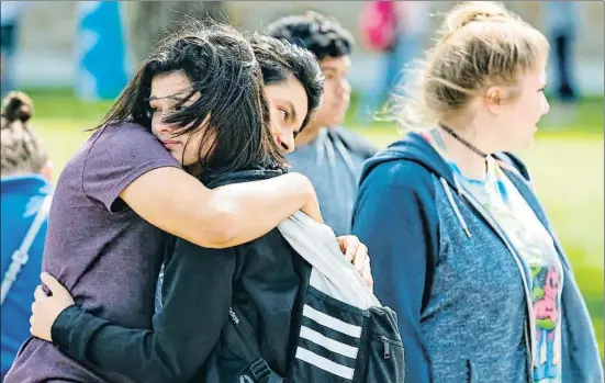  ?? MICHAEL CIAGLO / AP ?? Dos estudiante­s se abrazan en el exterior del instituto de Santa Fe mientras esperan para reunirse con sus familias
