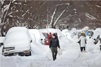  ??  ?? People navigate a snow-covered street in Chicago, Illinois, on Tuesday. Chicago residents are working to recover after a snowstorm coupled with lake-effect snow dumped more than 17 inches in some areas of the city. — AFP