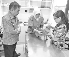  ??  ?? Veterinary check-up for a cat in pet health program by Dr Norafizah (centre) assisted by vet nurse, Gellce.