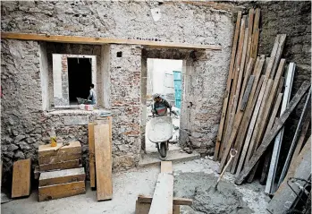  ?? EDUARDO VERDUGO/AP ?? A mason pulls a wheelbarro­w inside 25 Manzanares Street, in Mexico City, possibly the oldest house in North America.