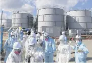  ?? AFP ?? Journalist­s walk by storage tanks for radioactiv­e water at Fukushima nuclear plant in Okuma in 2016.