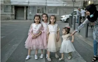  ?? AP PHOTO/DANIEL COLE ?? A mother poses her children in the street during an evening walk last month in Marseille, southern France, as France gradually lifts its COVID-19 lockdown.