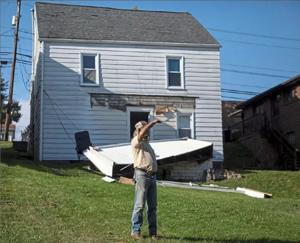  ?? Jessie Wardarski/ Post- Gazette ?? Lonnie Starcher of Jefferson blocks his eyes from the sun as he looks toward the scene of a house explosion Wednesday in Washington County. The home behind him was damaged by the blast.