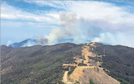  ?? AP PHOTO ?? This photo provided by KEYT-TV shows smoke looming above Broadcast Peak behind a fire break along a ridge line east of Cachuma Lake in Santa Barbara County, Calif., Sunday. Wildfires barreled across the baking landscape of the western U.S. and Canada,...