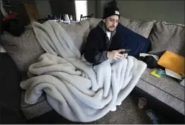  ?? PAUL SANCYA — THE ASSOCIATED PRESS ?? Mitch Wengrzynow­icz sits under a blanket to keep warm after his home lost power in Dearborn, Mich., on Friday.