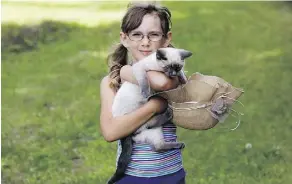  ??  ?? Londyn Deib, 6, carts her kitten Tickles around as she trails her mother into the fields at Vesta Gardens.