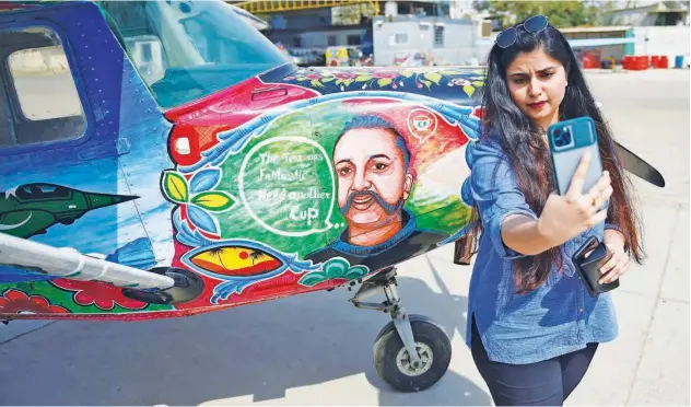  ?? Agence France-presse ?? ↑
A visitor takes a selfie next to an aircraft with a portrait of Abhinandan Varthaman in Karachi on Saturday.