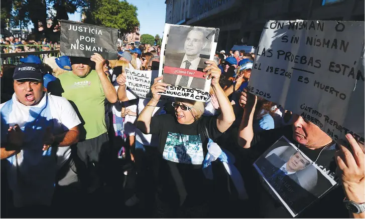  ?? (Reuters) ?? A WOMAN holds up a photo of the late Argentinea­n state prosecutor Alberto Nisman, during on the second anniversar­y of his murder in Buenos Aires on Wednesday. The sign at left reads: ‘Justice for Nisman.’
