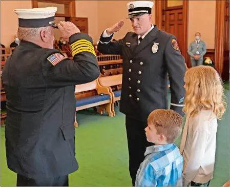  ?? SEAN D. ELLIOT/THE DAY ?? Norwich Fire Department Lt. Adam Griffin, right, salutes his father, Kevin Griffin, a past chief of the Clinton, N.Y., fire department, as his children Caitlyn, 8, and Ryan, 5, look on during his swearing-in ceremony Monday for his promotion to lieutenant.