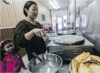  ?? DAVE SIDAWAY ?? Four-year-old Zya watches as her mother, Zhen “Lan” Liu, makes jian bing guo at Montreal Chinese Crêpes and Dumplings on Westminste­r Ave. in Montreal West. “The original popular one comes from the north part of China, in Tianjin,” explains Zhen, who...