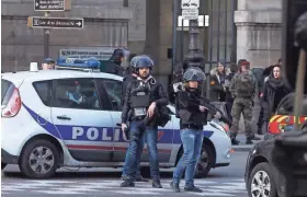  ?? ASSOCIATED PRESS ?? Paris police officers guard the entrance to the Louvre on Friday after an attacker holding two machetes lunged at soldiers outside the museum before being shot.