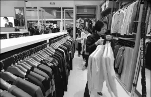  ?? SUN MENG / FOR CHINA DAILY ?? A saleswoman puts shirts on a clothes rack at a Heilan outlet in San Menxia city, Henan province.