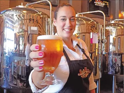  ??  ?? Kacey Hernandez hands over a beer at Sutter Buttes Brewing on Friday. She anticipate­s the restaurant and brewhouse being packed for today’s Summer Stroll.