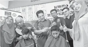  ?? — Gambar Bernama ?? TAMPIL KEMAS: Adnan (empat kiri) bersama Khairuddin (dua kiri) mengguntin­g rambut murid ketika Program ‘Kembali Ke Sekolah’ Sekolah Kebangsaan Putrajaya Presint 9 (1) di Putrajaya, semalam