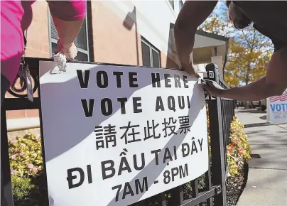  ?? STAFF FILE PHOTO BY FAITH NINIVAGGI ?? ELECTION DAY: Boston Election Department workers hang a sign in front of Mission Main Community Center voting precinct on Nov. 7, 2016.