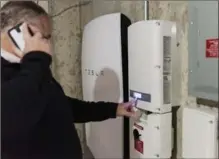  ?? IAN THOMAS JANSEN-LONNQUIST, BLOOMBERG ?? A customer inspects a Tesla Motors Powerwall unit inside a home in Monkton, Vermont.