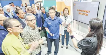  ?? — Bernama photo ?? Fahmi (second left) is briefed on the e-Farmasi mobile applicatio­n following the launch ceremony at Multimedia University’s TM Digital Academy.